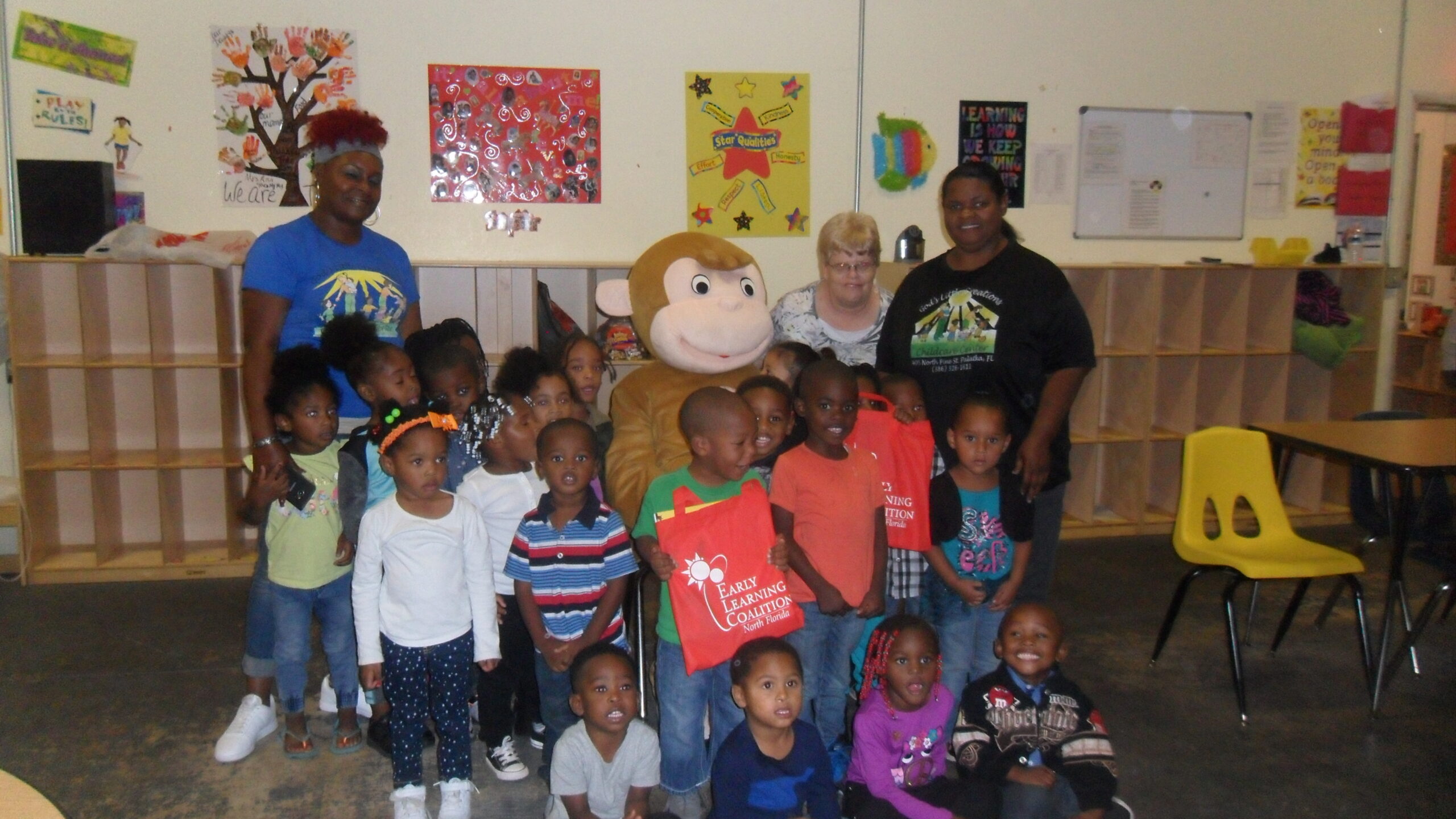 Curious George and ELC of North Florida volunteers deliver book bags to children at God’s Little Creations Learning Center in Palatka.